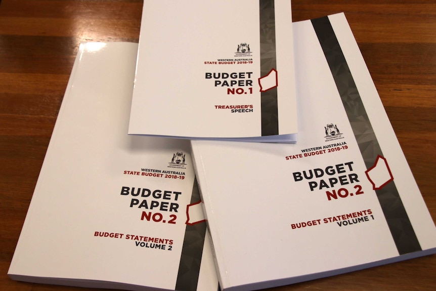Three white 2018-19 WA state budget books lie on a brown table.