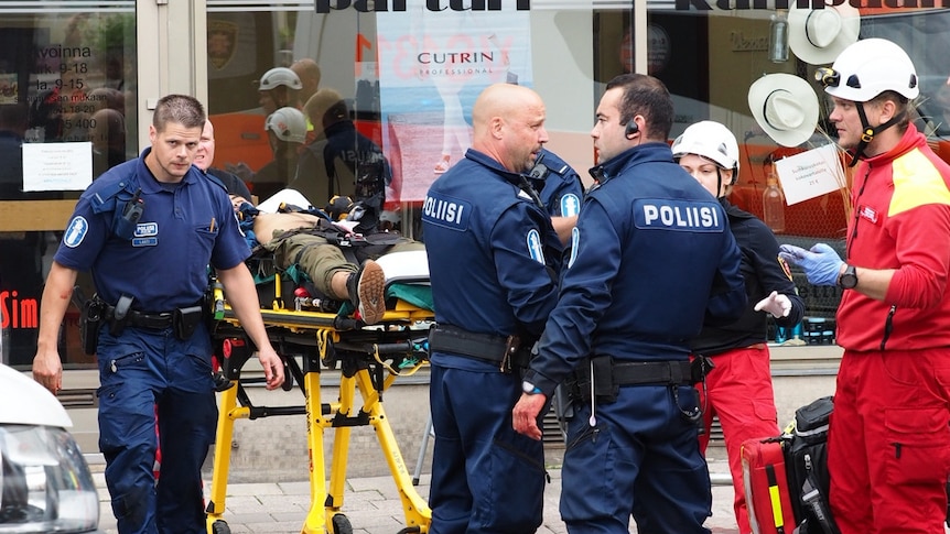 Police escort an injured man believed to be the suspect on a stretcher.