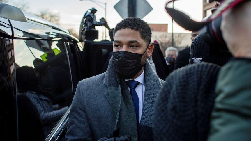 Jussie Smollett standing outside court with a mask on