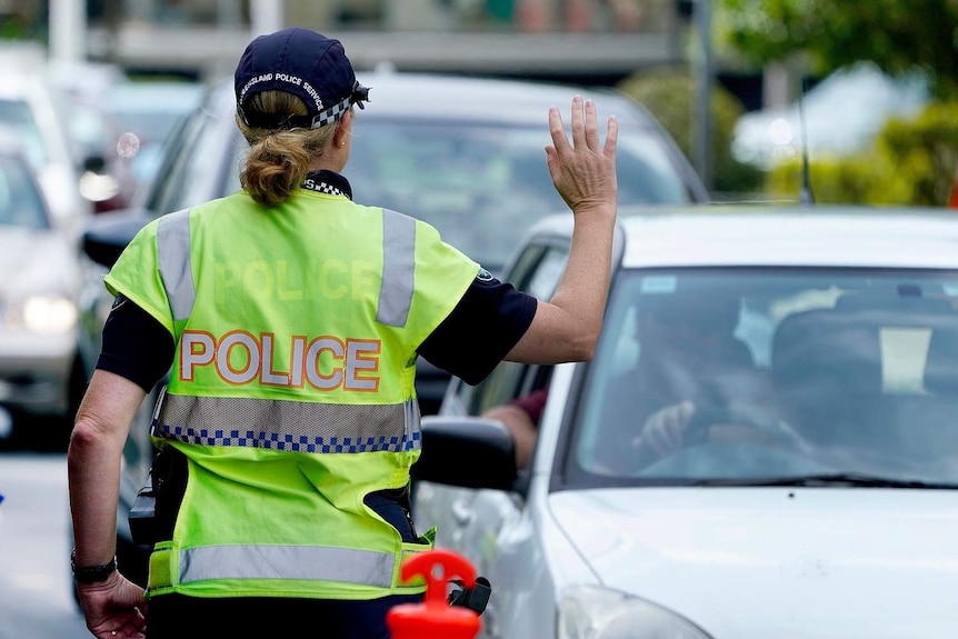A police officer stops a driver at a checkpoint at Coolangatta on the Queensland - New South Wales border.