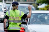 A police officer stops a driver at a checkpoint at Coolangatta on the Queensland - New South Wales border
