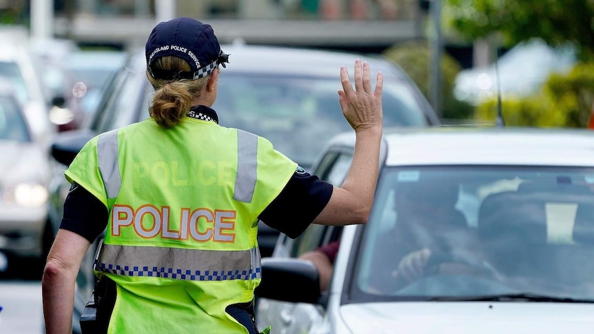 A police officer stops a driver at a checkpoint at Coolangatta on the Queensland - New South Wales border.