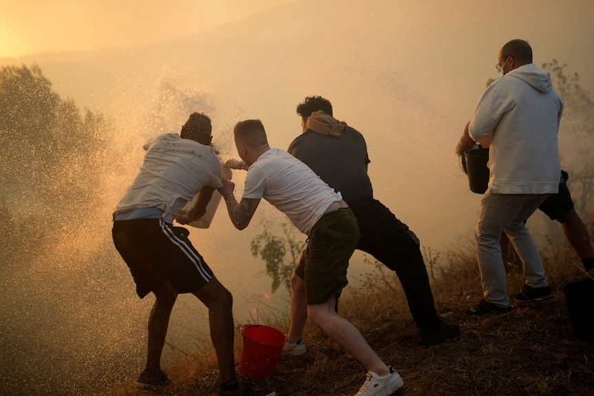 Men in white shirts fight an orange blaze of fire 