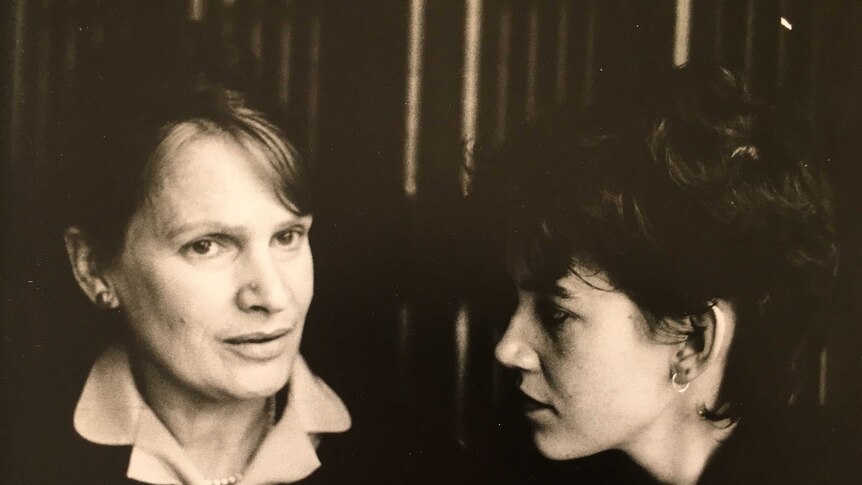 black and white image of two women.  Woman on left looking off to side, while woman on right looking at woman on left.