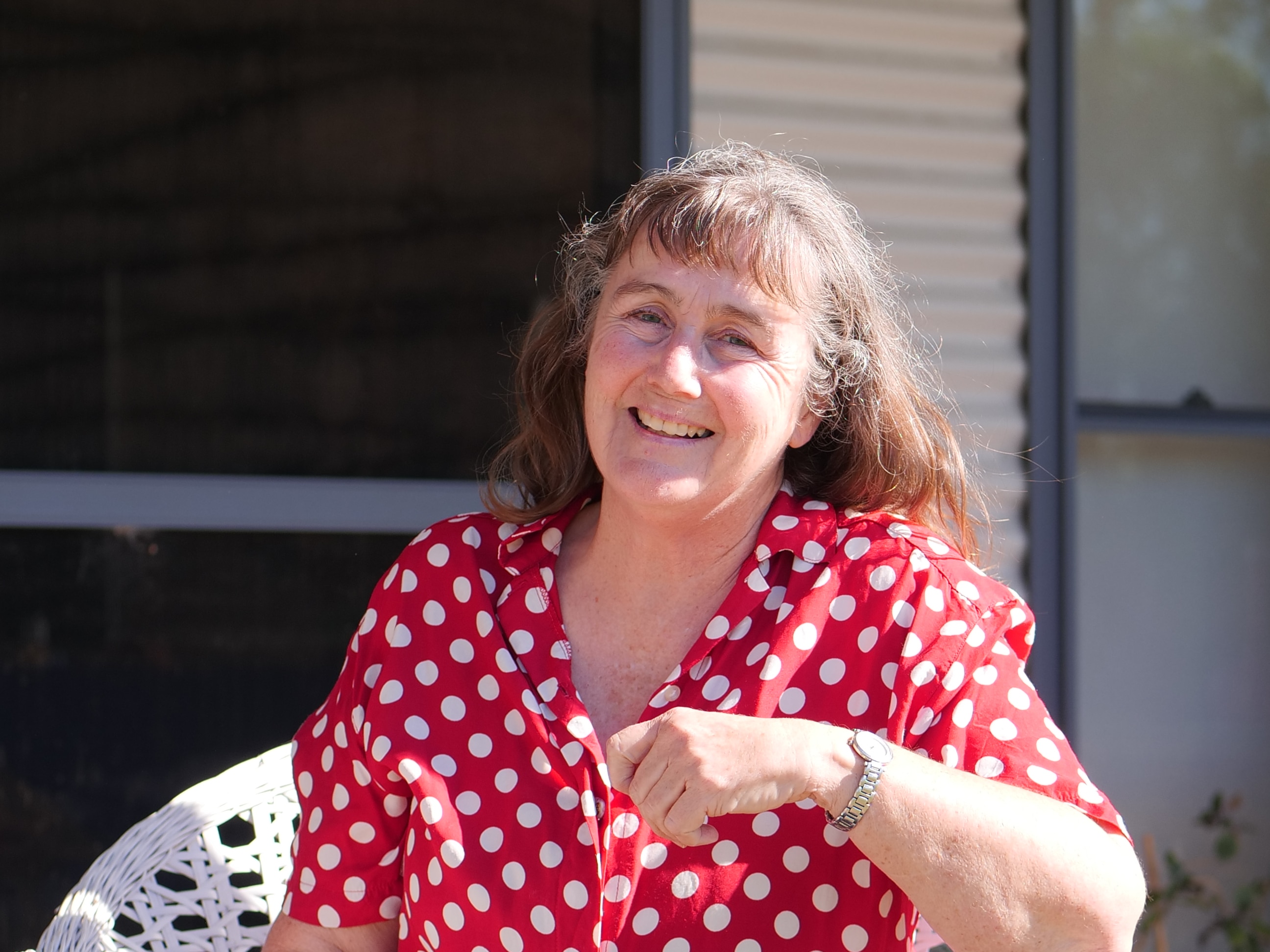 Woman in white and red polkadot blouse smiling at camera. 