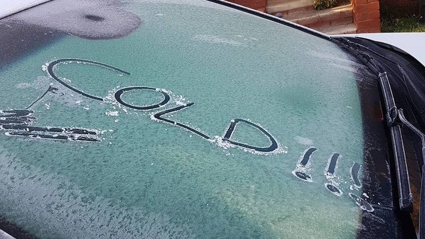 Cold!! is written on a frosty car windscreen.