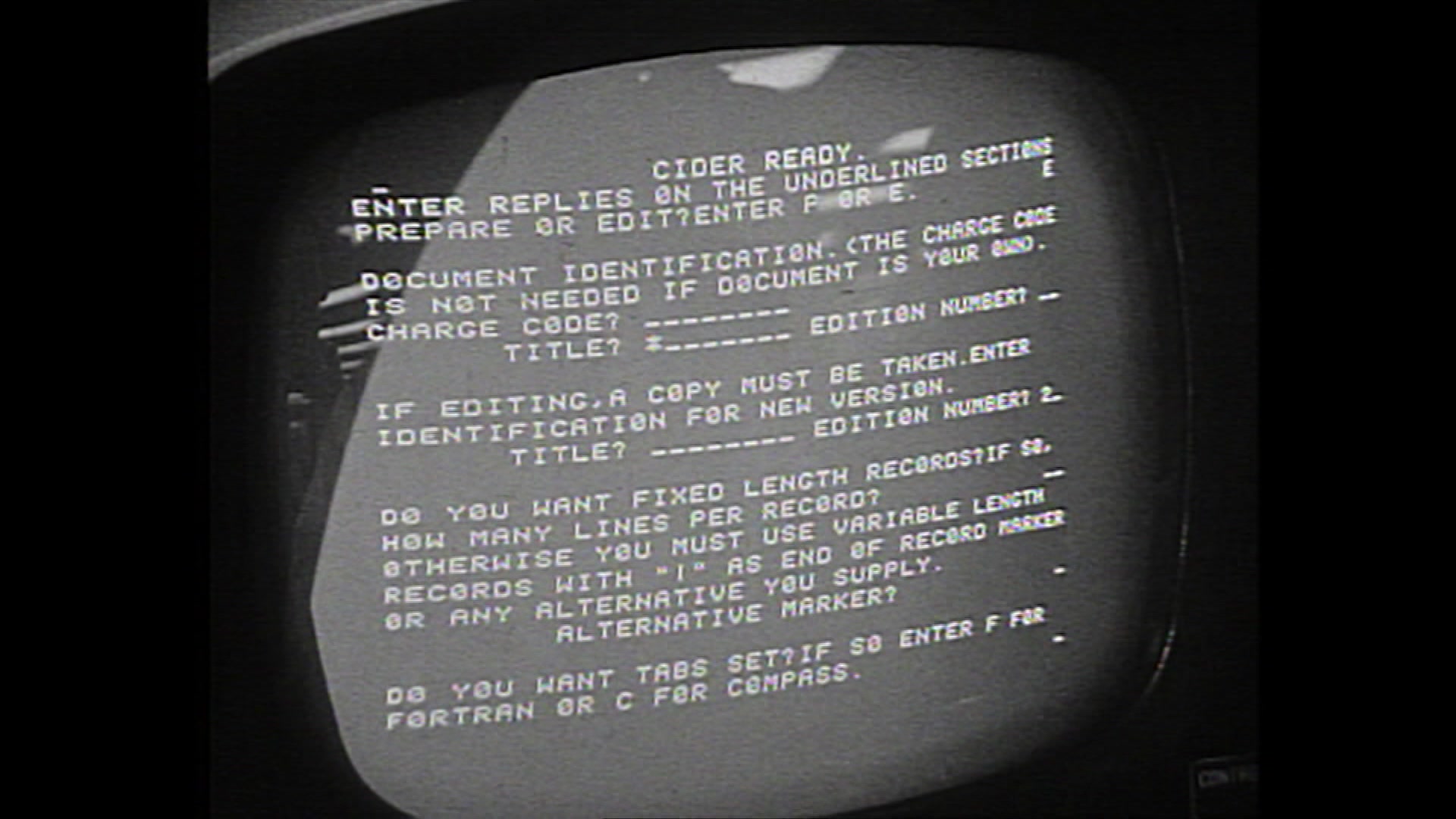White text on a black computer screen showing words and code in the 1960s