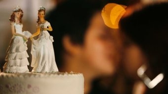 Kue pengantin dengan latar belakang pasangan yang menikah buram