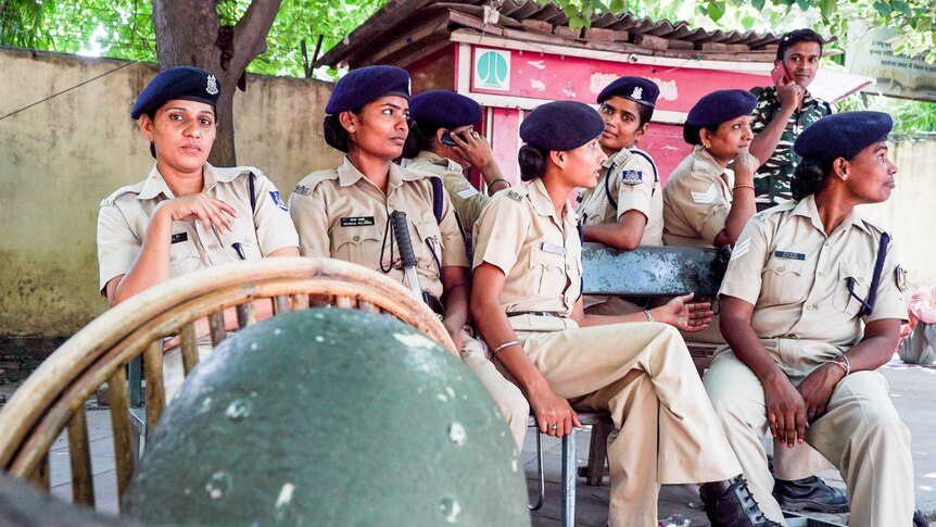A group of policewomen sit on chairs outside