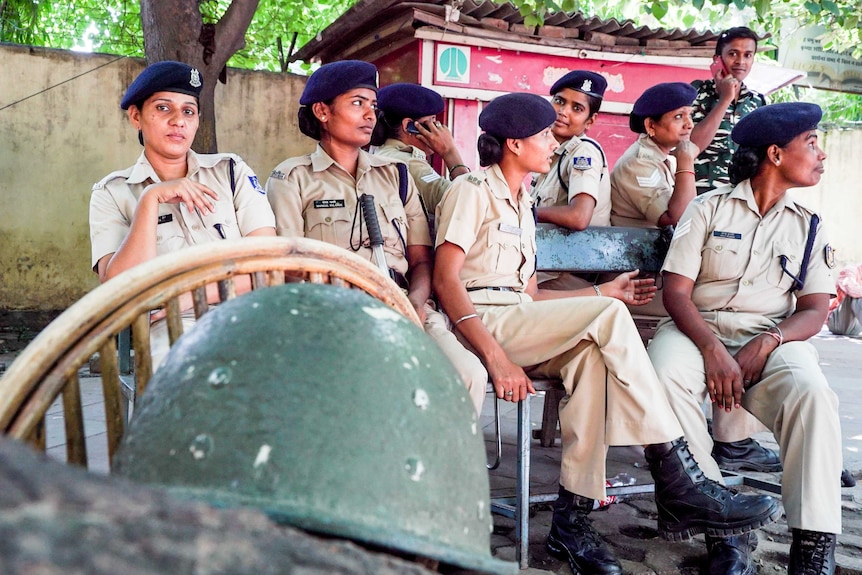 A group of policewomen sit on chairs outside