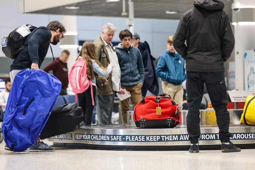 People collect their bags at the carousel at the Brisbane airport.