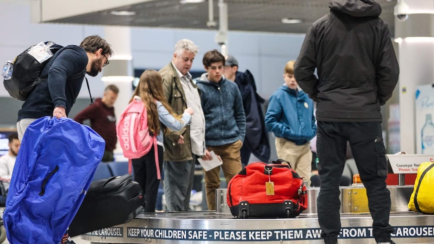 People collect their bags at the carousel at the Brisbane airport.