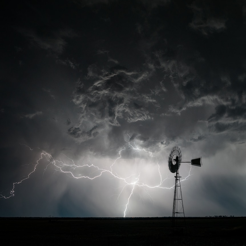 Lightning strikes behind a windmill.