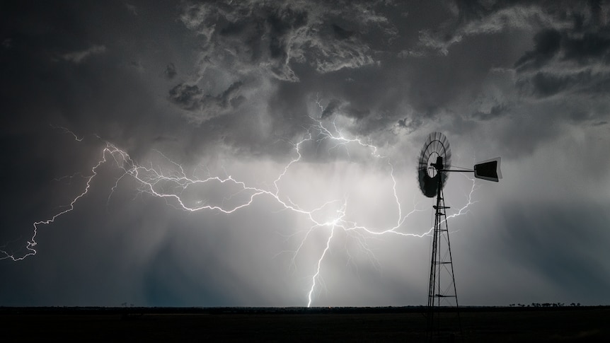 Lightning strikes behind a windmill.