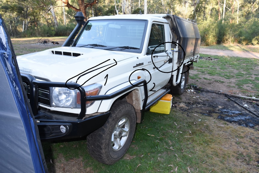 The front passenger side of a white ute, with damage to the passenger mirror and rear canopy.