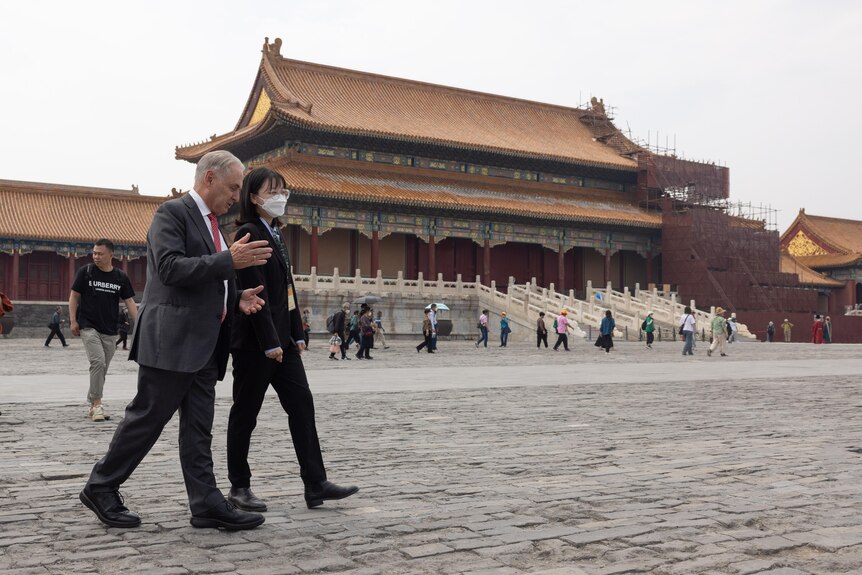 Australian trade minister Don Farrell walks through a courtyard of China's Forbidden City with a guide.
