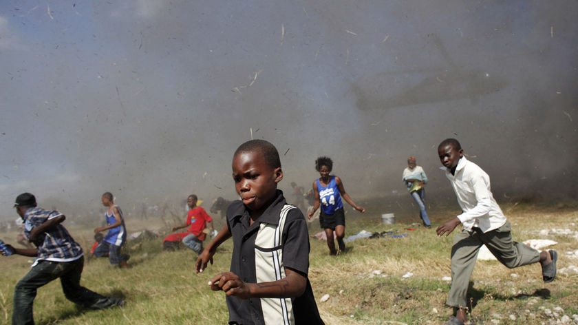 Children run away from an helicopter delivering aid in Haiti after an earthquake