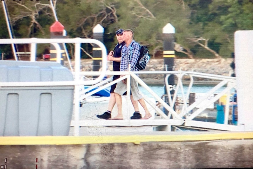 Fisherman is escorted by water police to waiting paramedics.