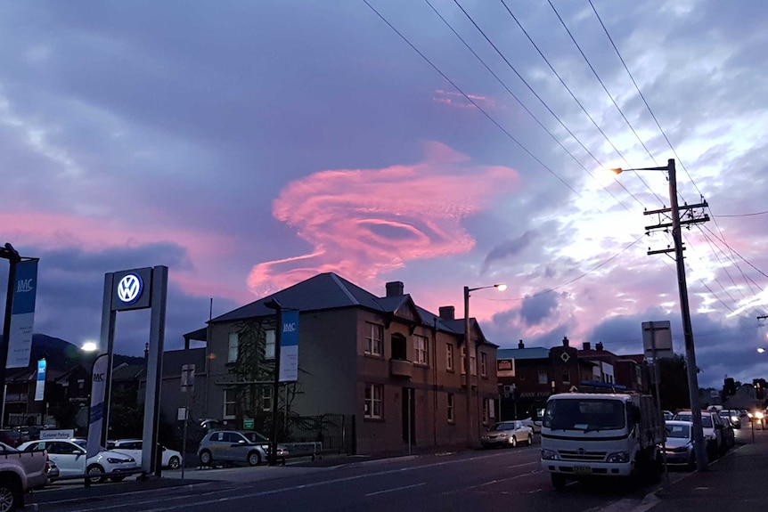 Bright pink cloud in a circle shape over a large pub at dusk