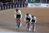 Three men sprint around a velodrome on their bikes.