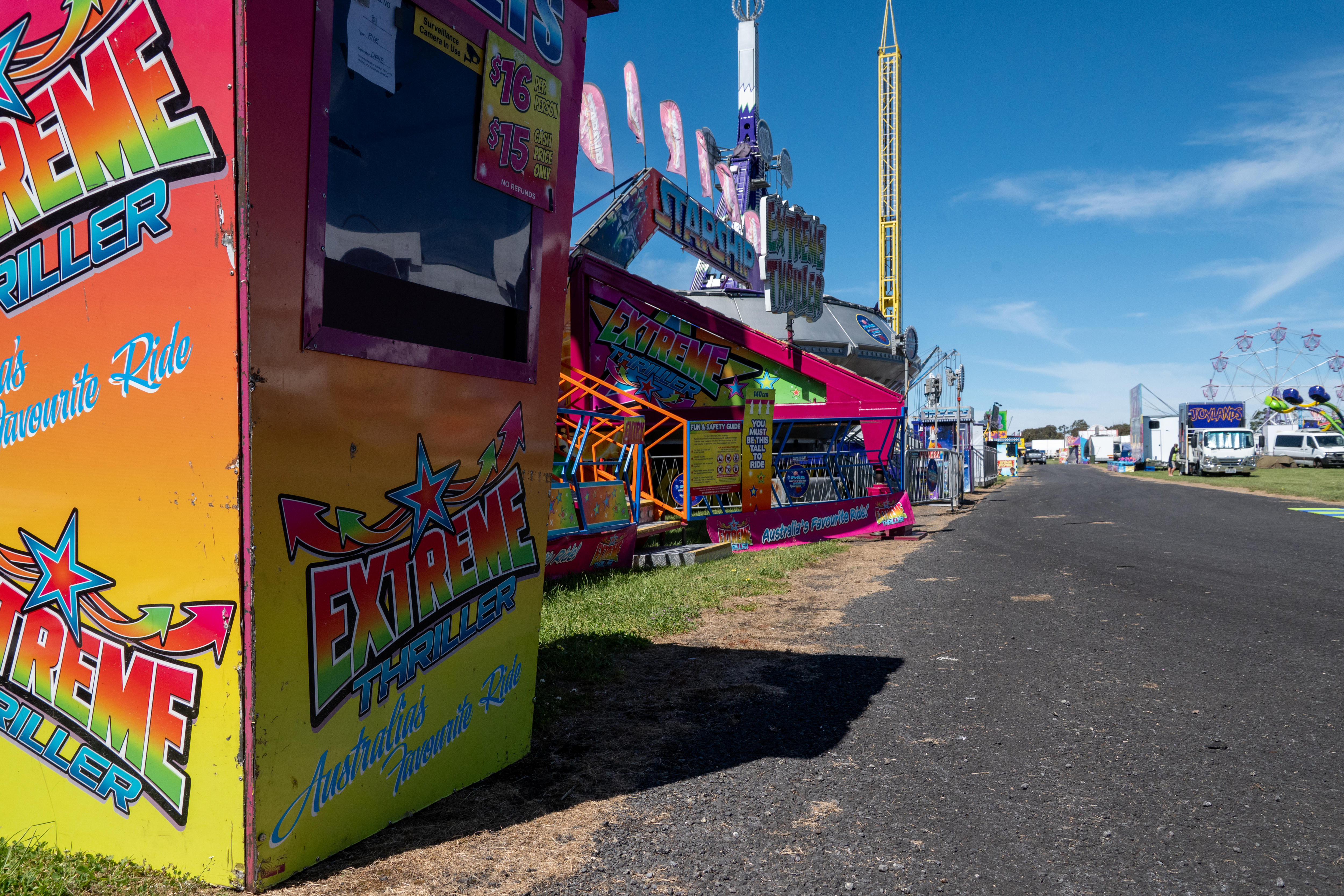 Side shows along a bitumen road with ferris wheel in backrgound