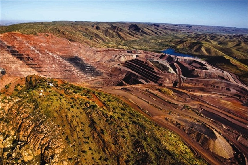 An aerial photo of a mine site with mounds of red dirt.
