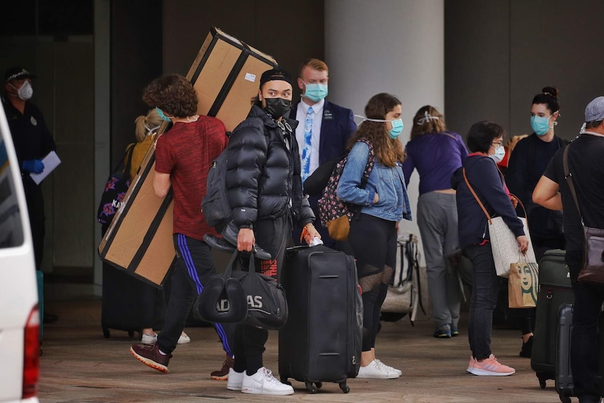 Travellers gathered on a hotel driveway wearing face masks