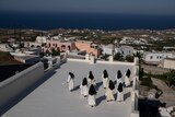 a group of nuns walk along a rooftop terrace
