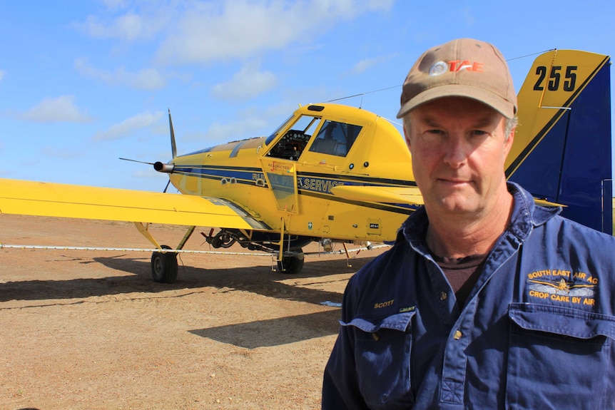 Scott Mackie with a crop spraying plane in the background.