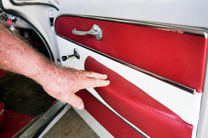 Man's hand touches the neat trim on interior Holden car door