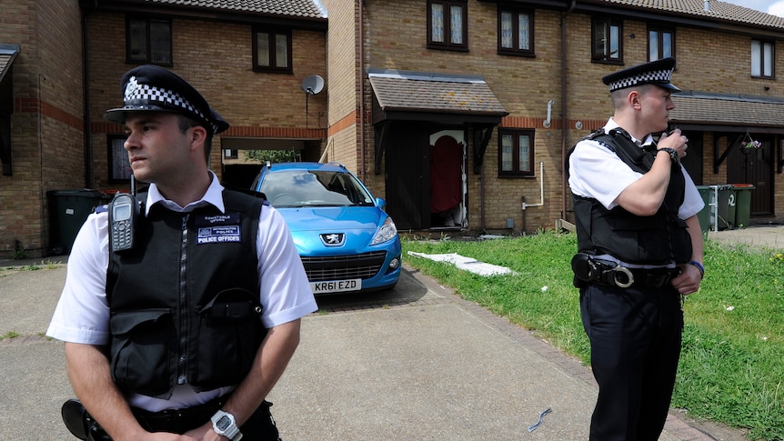 Police officers stand outside a house in Stratford in east London.