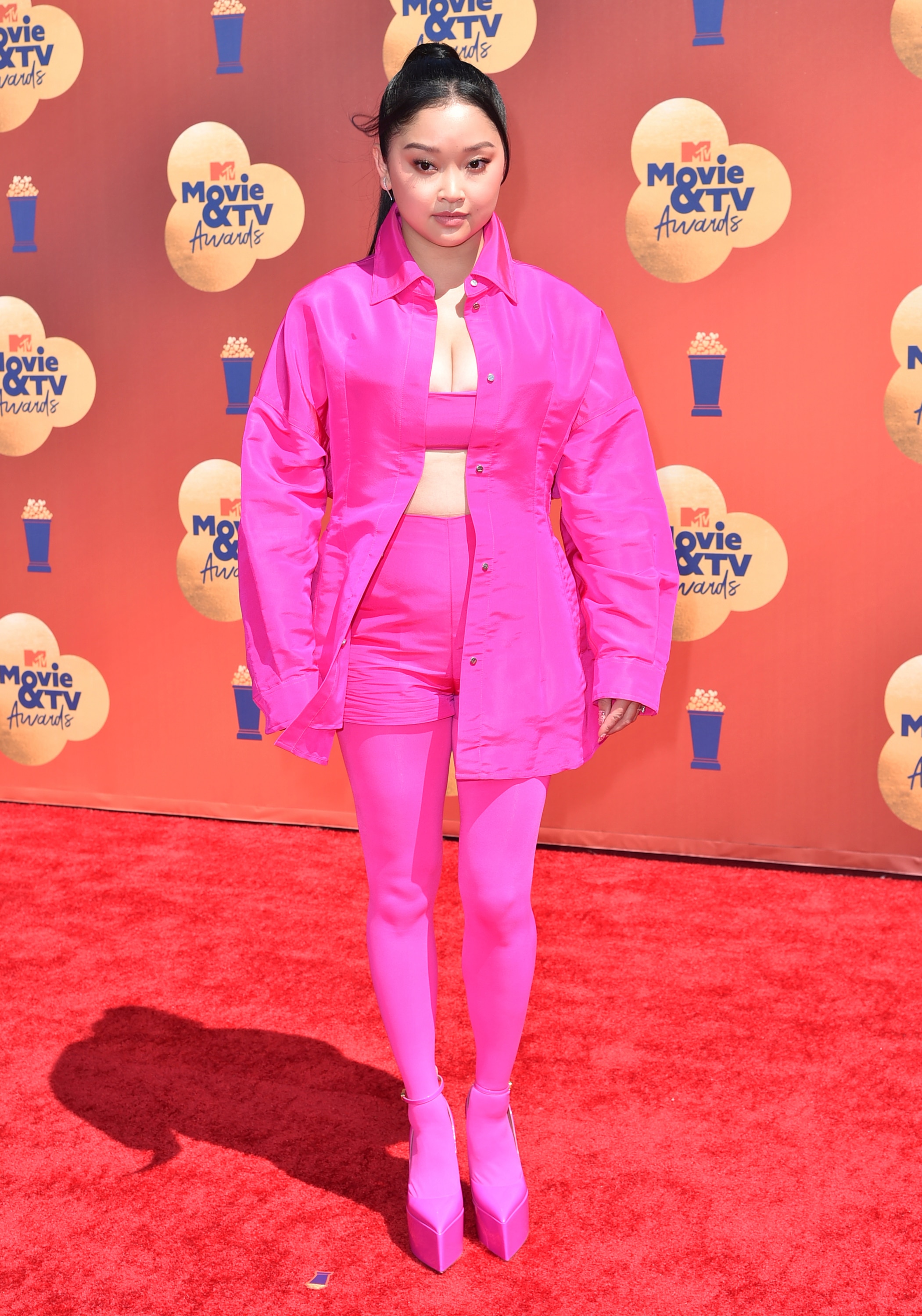 Lana poses on the red carpet in a jacket, shorts, top, heels and tights all in the same shade of hot pink. 