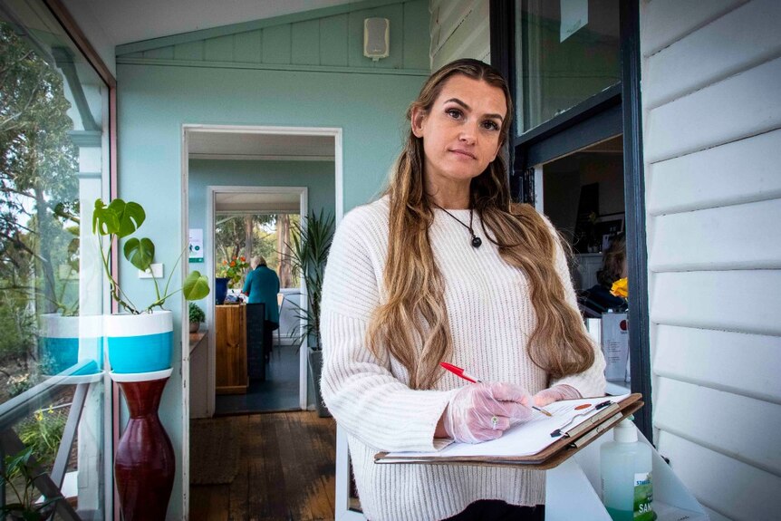 A woman holds a clipboard at a restaurant