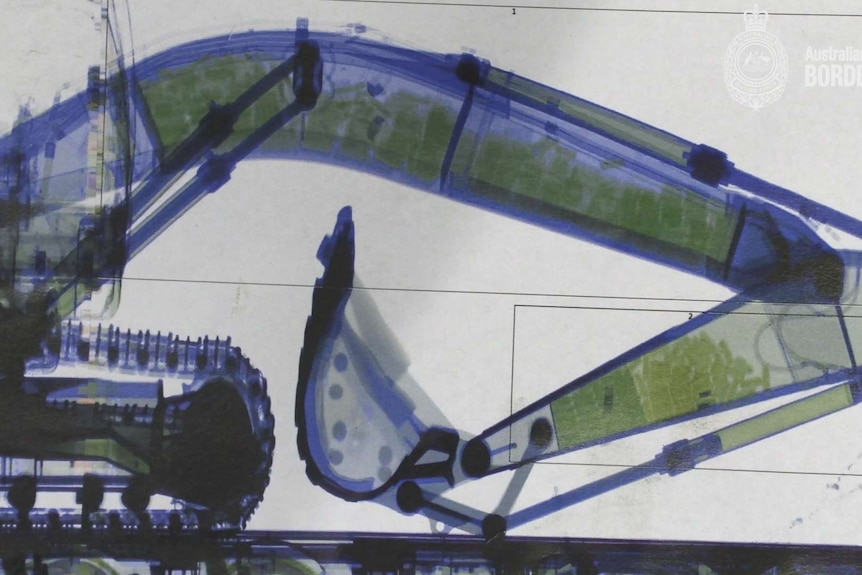An x-ray picture of an excavator with many little visible packages in its arm.