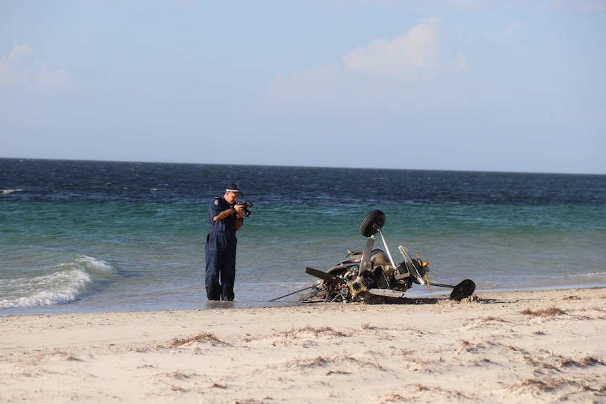 A police officer takes photos of the gyrocopter wreckage.
