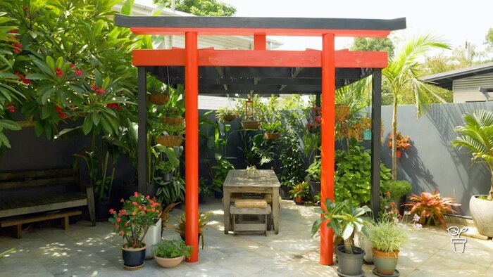 Tropical garden with red pergola covering an outdoor table
