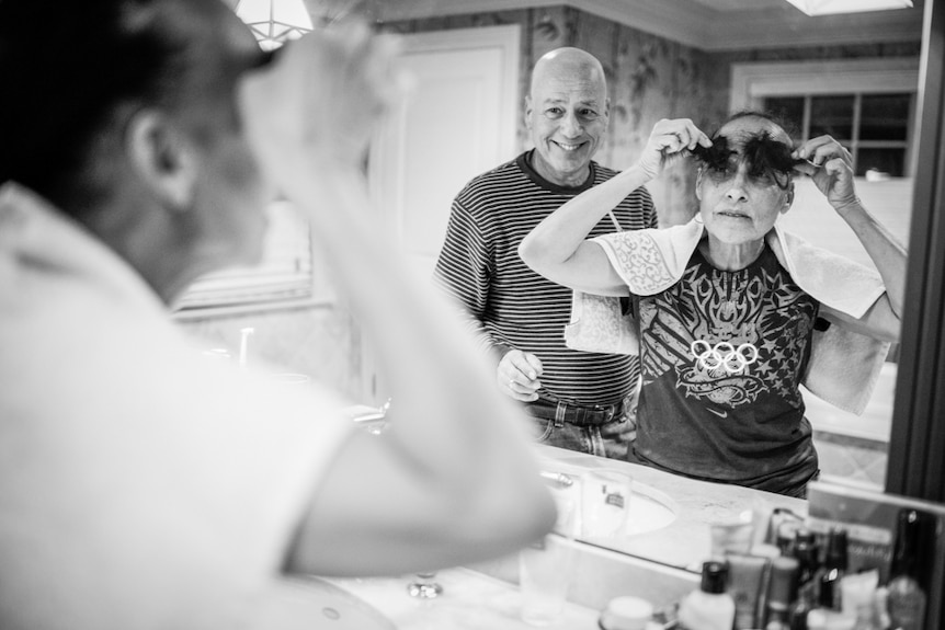 Laurel  Borowick looks in the mirror, holding pieces of black hair above her eyes.