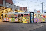A colourfully decorated tram pulls out of a depot