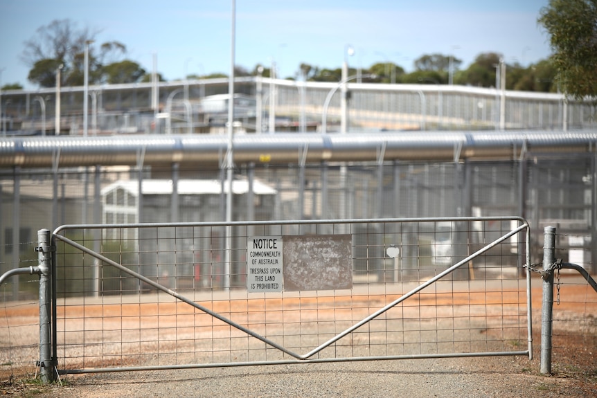 Shot of steel gate with sign saying "Commonwealth of Australia" outside a detention centre