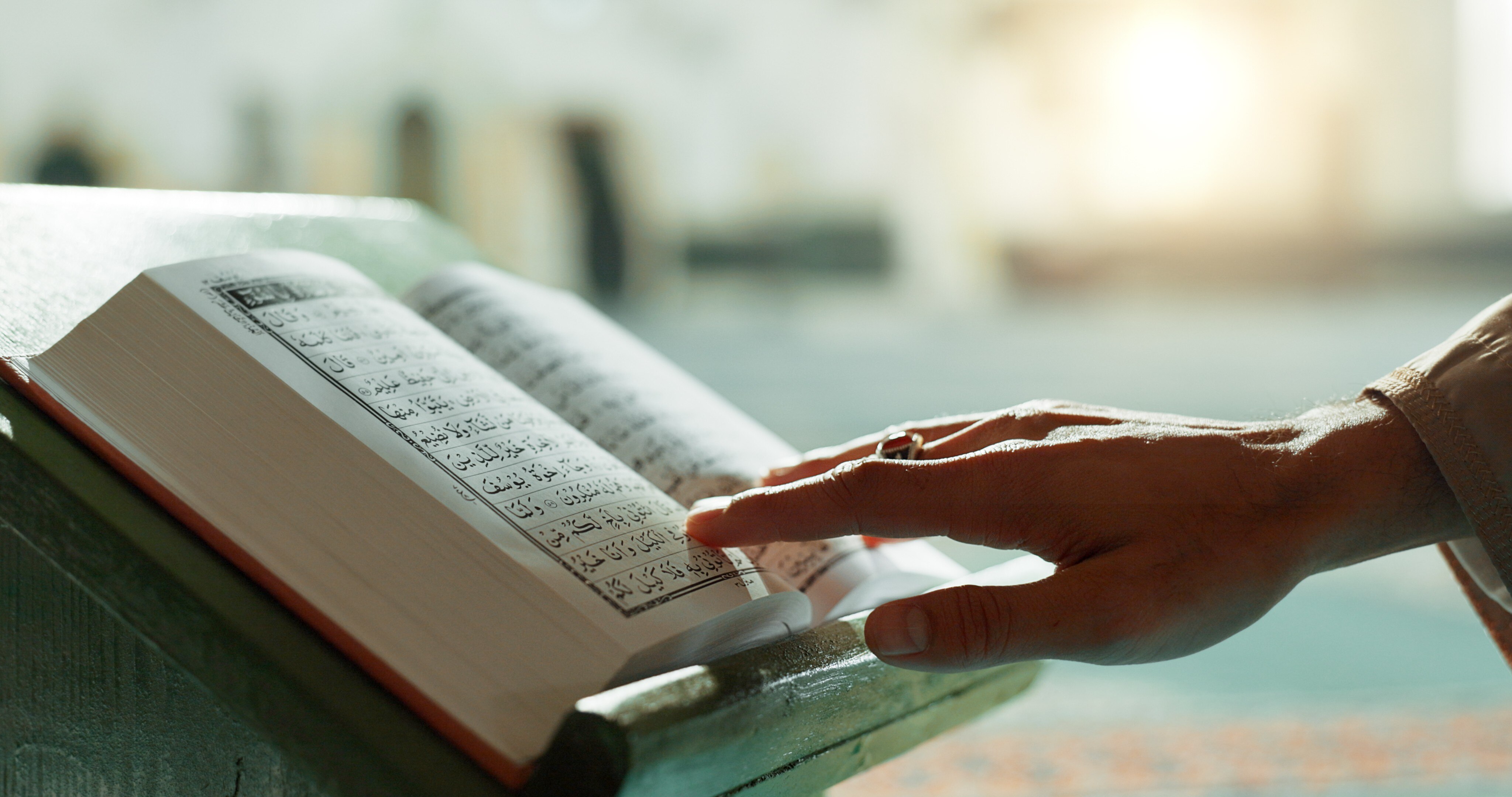Hand reaching out, touching a Qurʾān