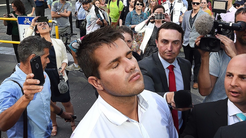 Gable Tostee shuts his eyes as he leaves the Supreme Court and reporters jostle to ask him questions.