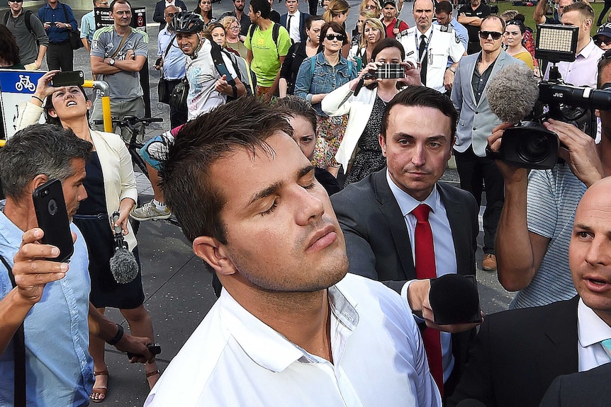 Gable Tostee shuts his eyes as he leaves the Supreme Court and reporters jostle to ask him questions.