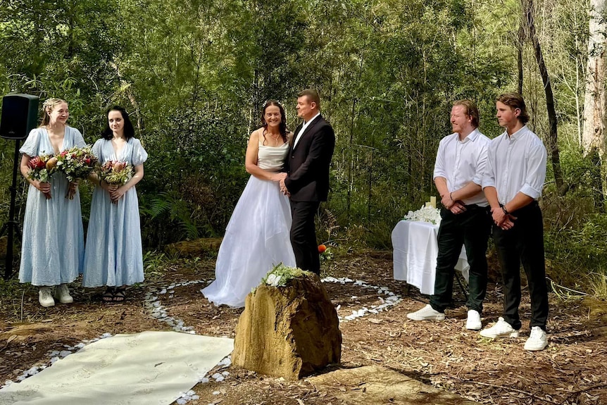 Newlyweds and bridal party in a bush setting.