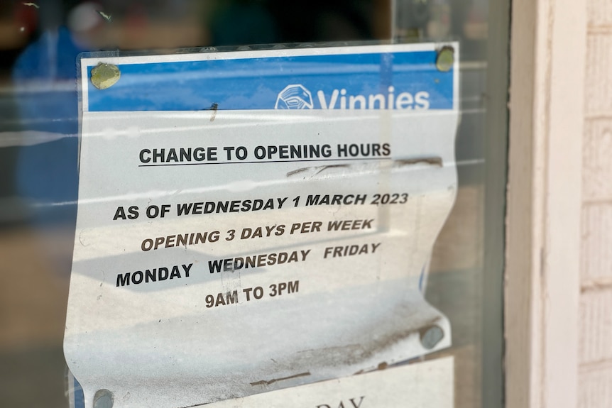A sign in  a shop window with details on opening hours.
