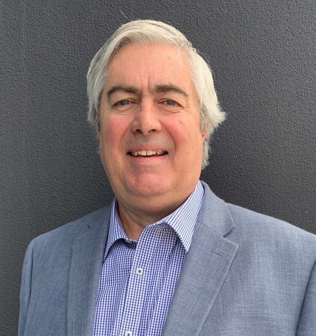 A man with silver hair in a suit jacket.  