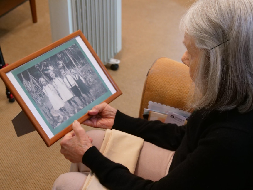 old lady looking at old picture of children.