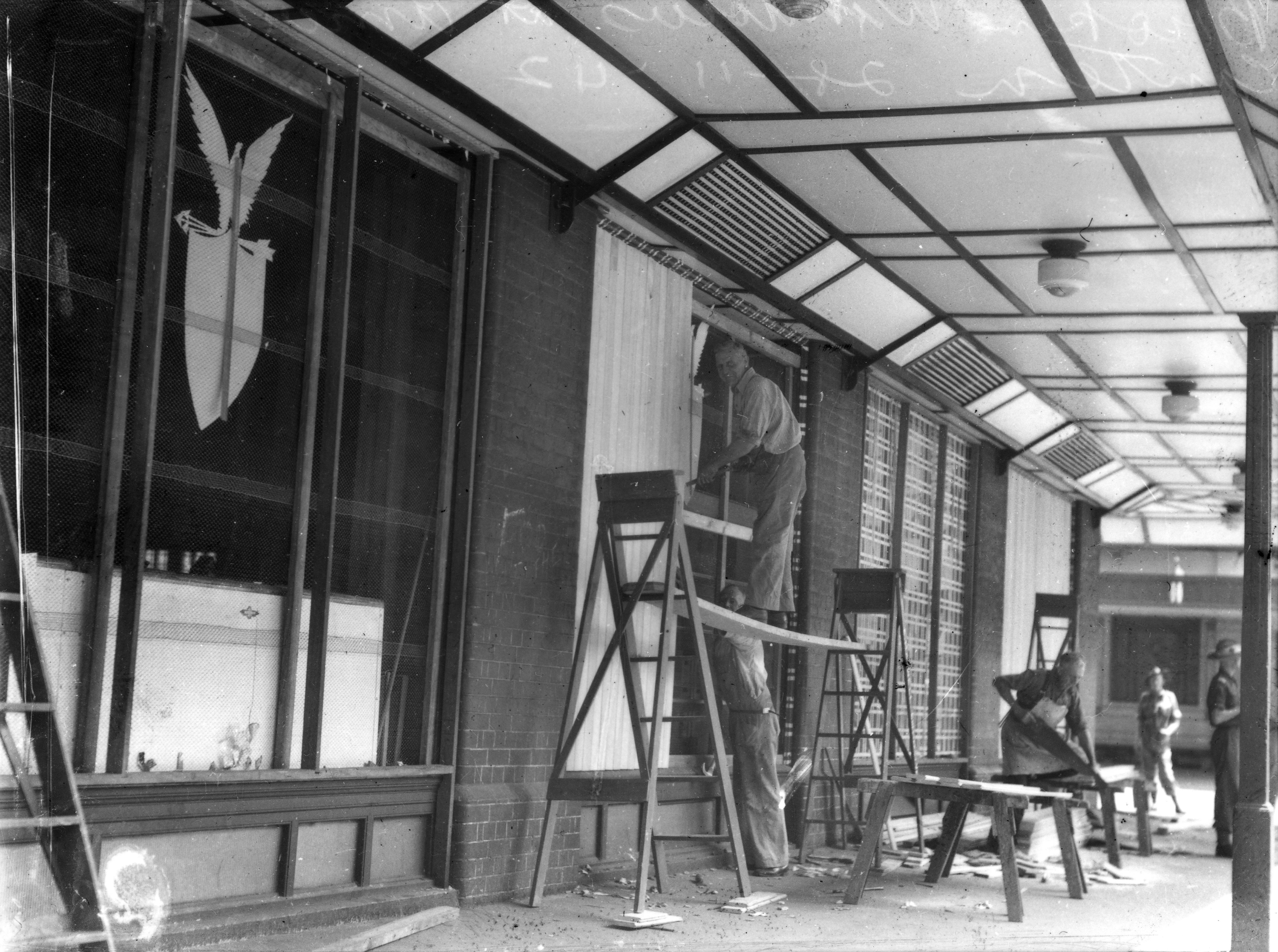 Black and white photo of workers repairing windows in a building.