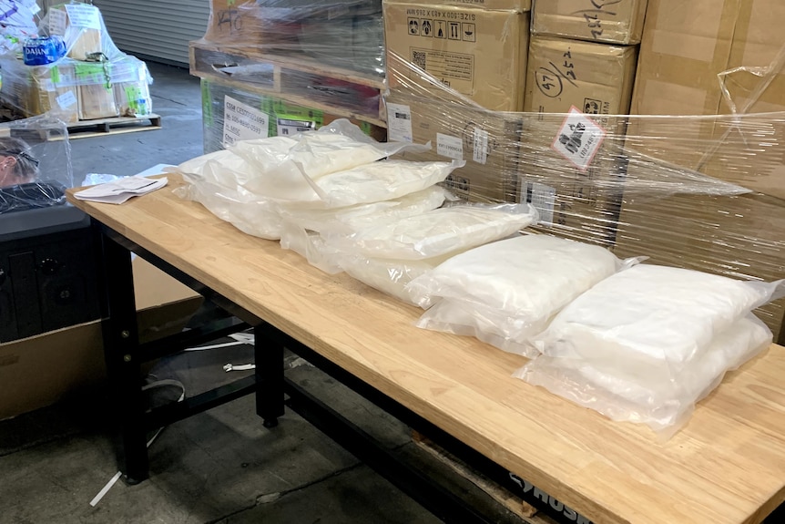 A table with bags of multiple large bags of a white substances.