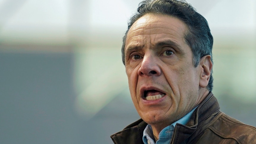 New York Governor Andrew Cuomo with his mouth open looking right and up while wearing a jacket over a blue shirt