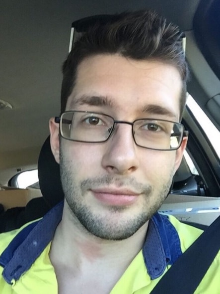 A man wearing glasses while sitting in a car.